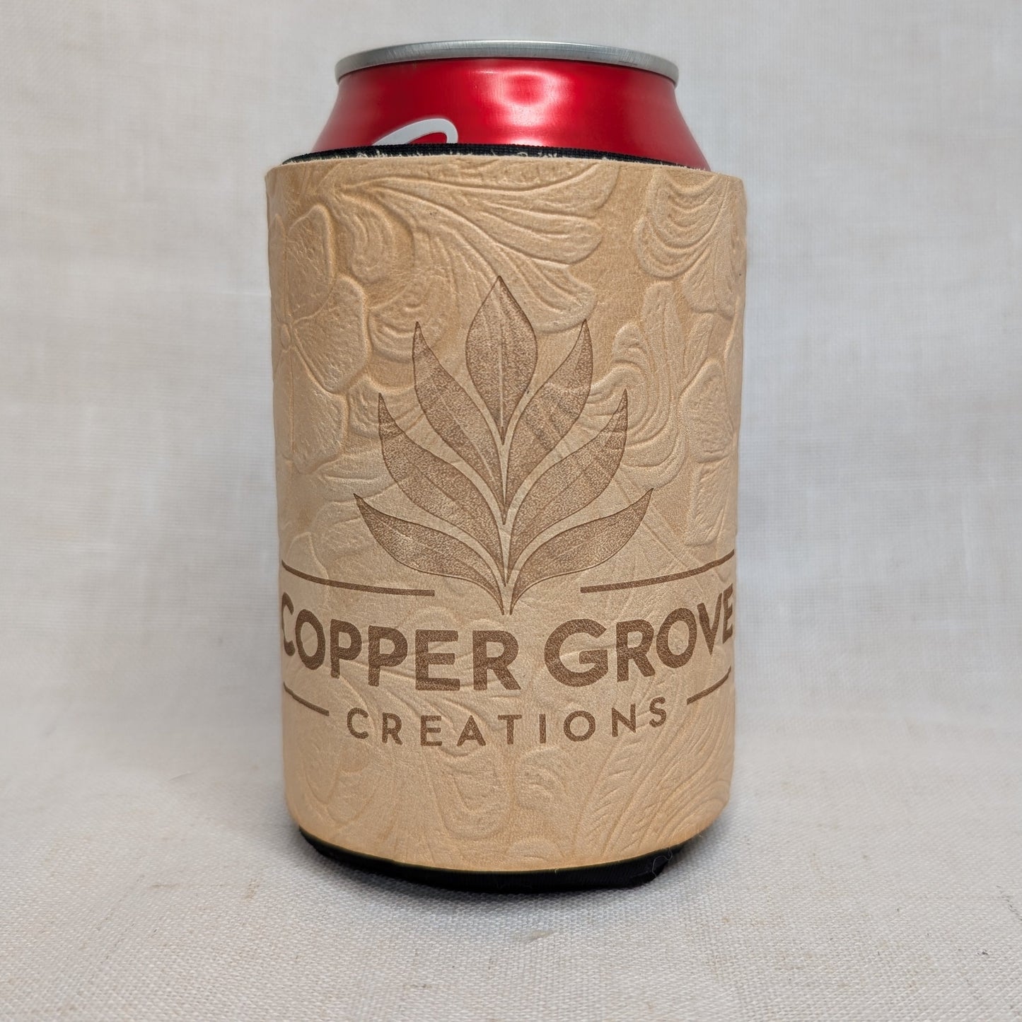 Personalized tan embossed floral leather can cooler featuring the Copper Grove Creations logo and a red beverage can.