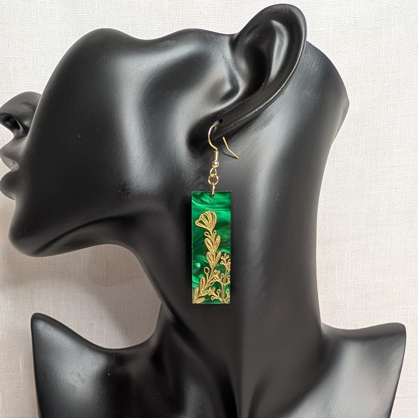 Green marbled rectangular dangle earring from The Gilded Garden Collection with an intricate gold floral design displayed on a black jewelry stand.