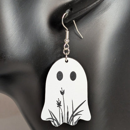 White ghost-shaped dangle earring with a black floral design, handmade Halloween jewelry.