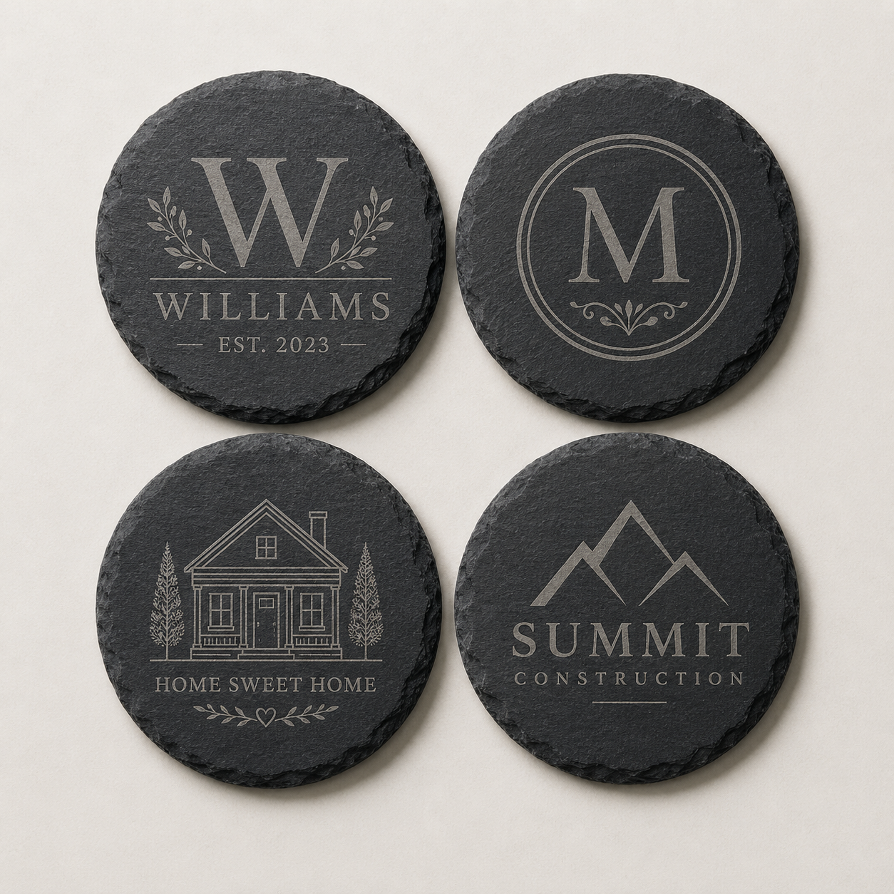 Set of four custom engraved round slate coasters featuring a family name, monogram, home design, and business logo.