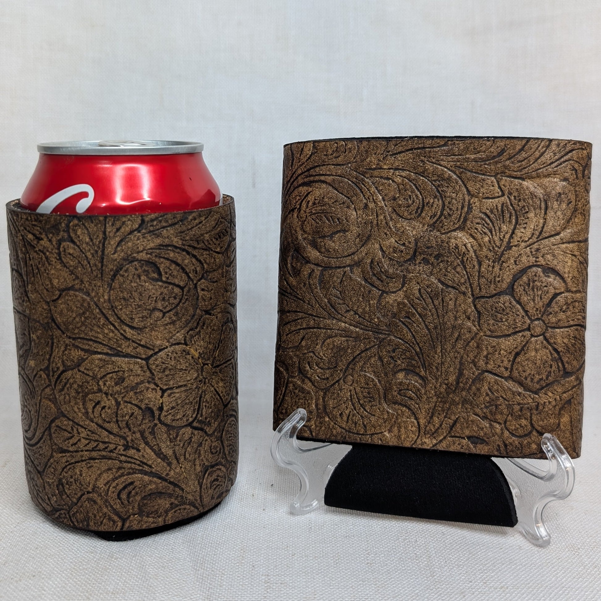 Brown embossed floral leather can cooler displayed with a matching leather sample and red beverage can on a light background.