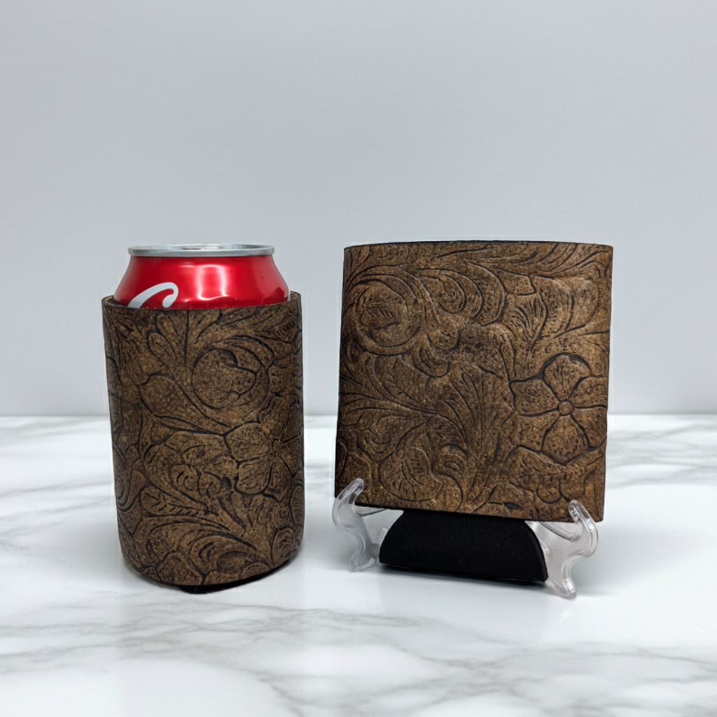 Brown embossed floral leather can cooler with a red beverage can displayed beside a matching leather sample on a light marble background.