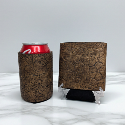 Brown embossed floral leather can cooler with a red beverage can displayed beside a matching leather sample on a light marble background.