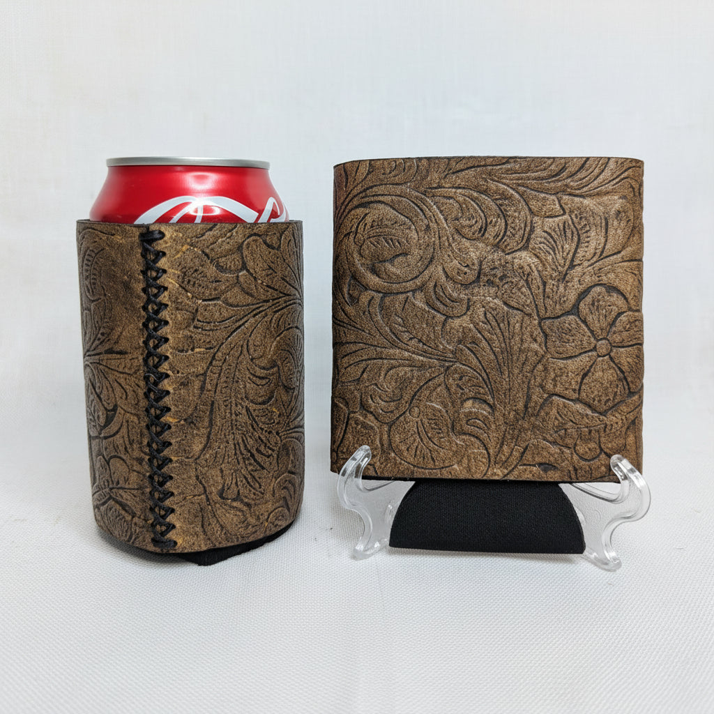 Brown embossed floral leather can cooler with hand-stitched side seam, red beverage can, and matching embossed leather sample on a display stand.