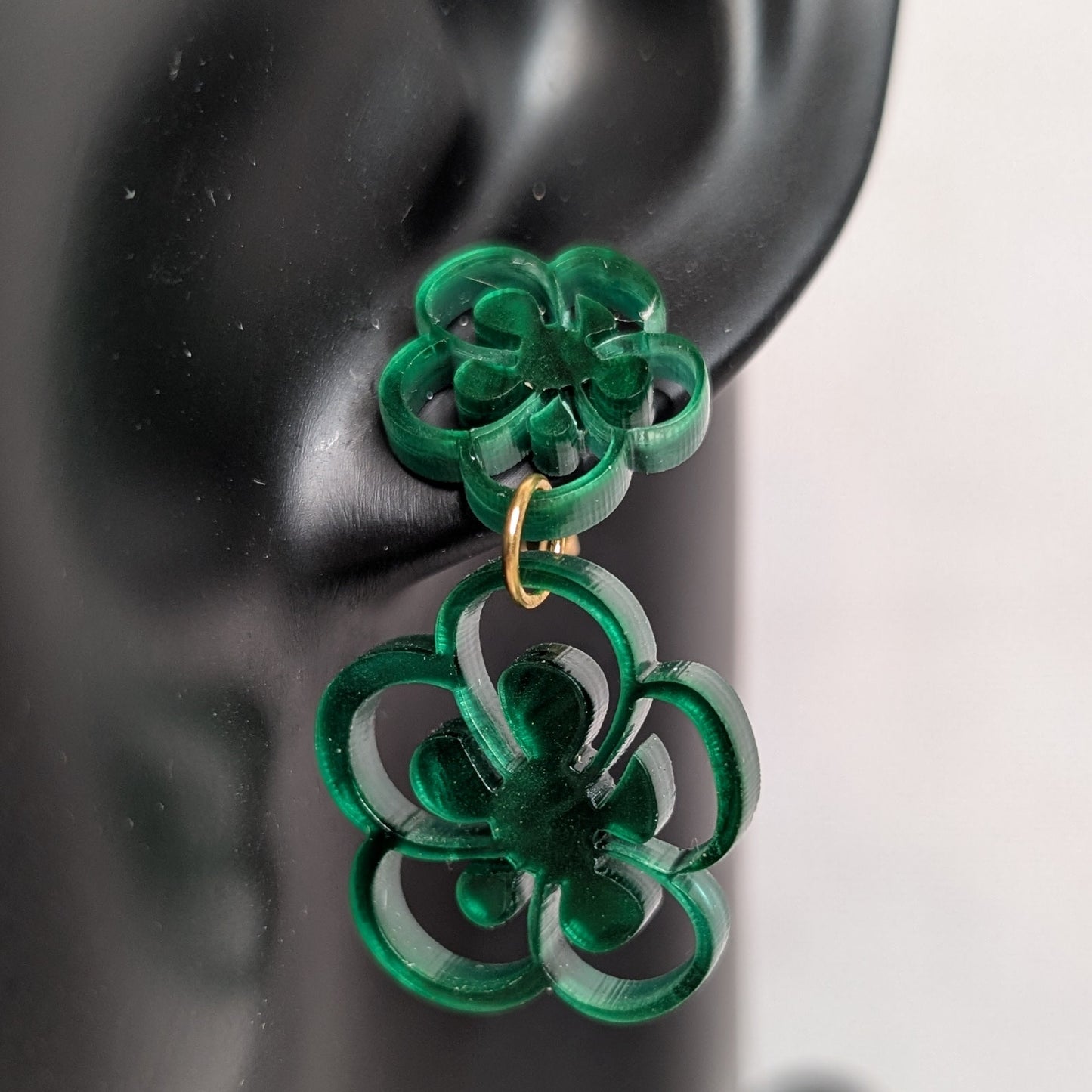 Close-up of green marbled flower bloom dangle earrings with layered acrylic floral shapes and gold connectors.