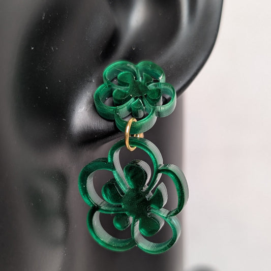 Close-up of green marbled flower bloom dangle earrings with layered acrylic floral shapes and gold connectors.