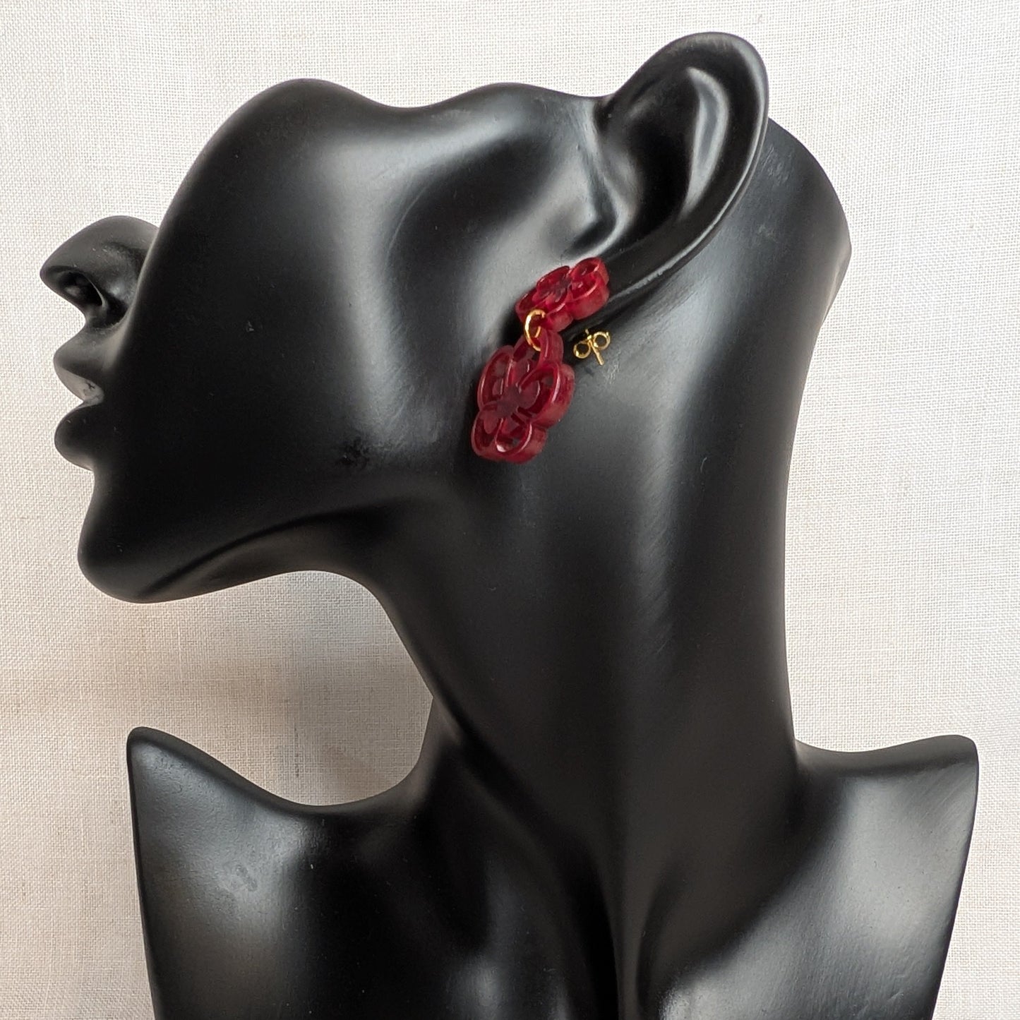 Green marbled flower bloom acrylic dangle earring with layered floral shapes displayed on a black jewelry stand.