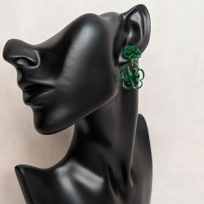 Green marbled flower bloom acrylic dangle earring with layered floral shapes displayed on a black jewelry stand.