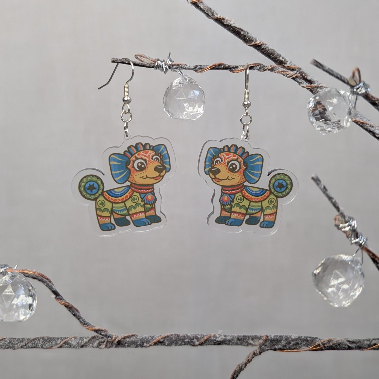 Multicolored dog Alebrije dangle earrings featuring bright Mexican folk art patterns in blue, orange, green, and yellow.