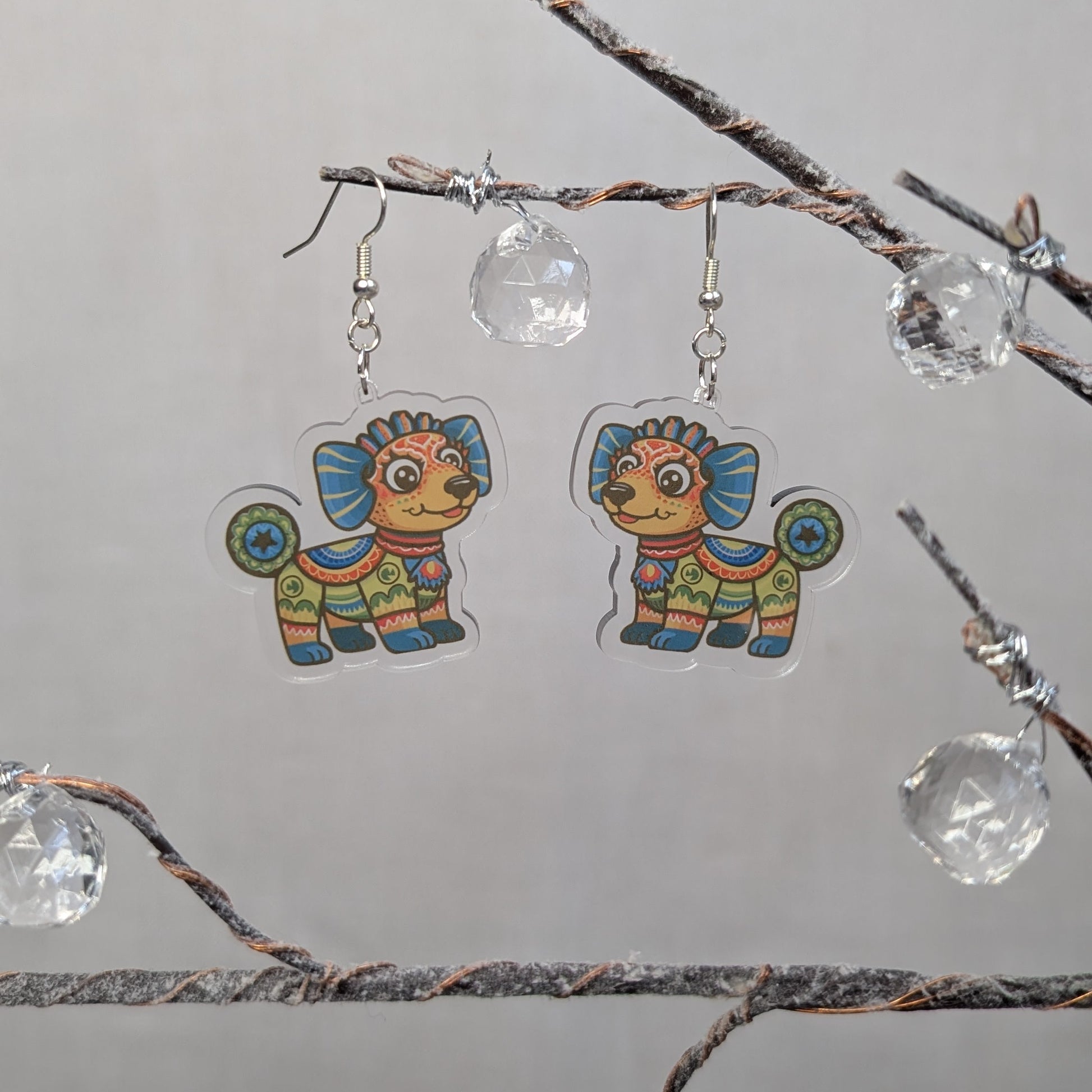 Multicolored dog Alebrije dangle earrings featuring bright Mexican folk art patterns in blue, orange, green, and yellow.