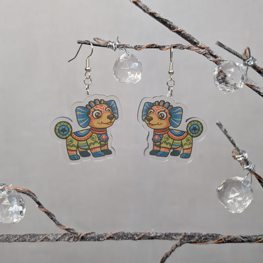 Multicolored dog Alebrije dangle earrings featuring bright Mexican folk art patterns in blue, orange, green, and yellow.