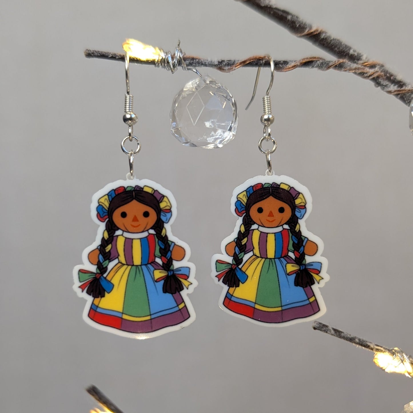 Pair of colorful Muñeca Mexican doll acrylic dangle earrings with braided hair and bright traditional dresses.
