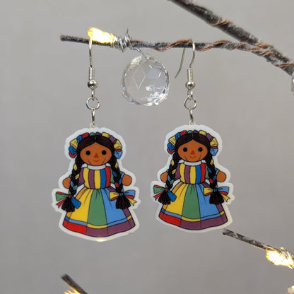 Pair of colorful Muñeca Mexican doll acrylic dangle earrings with braided hair and bright traditional dresses.