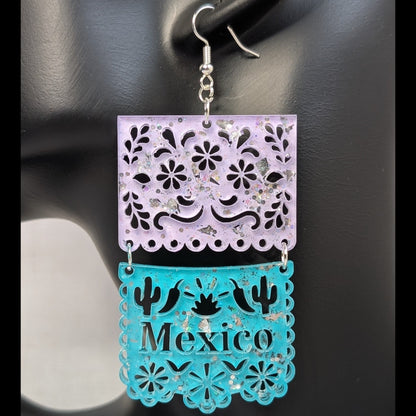 Close-up of turquoise and pink Papel Picado Mexico dangle earring with floral cutouts and cactus details.