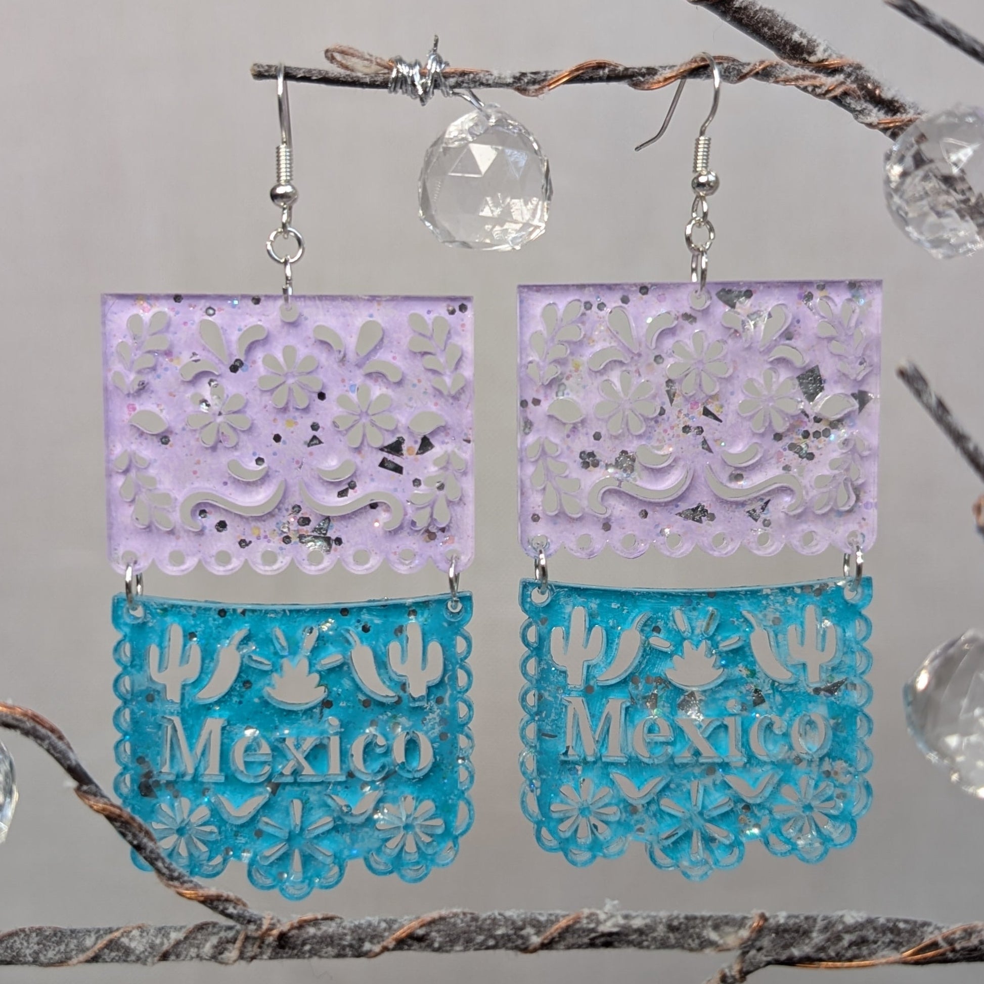 Turquoise and pink Papel Picado Mexico dangle earrings with floral cutouts, cactus details, and decorative scalloped edges.