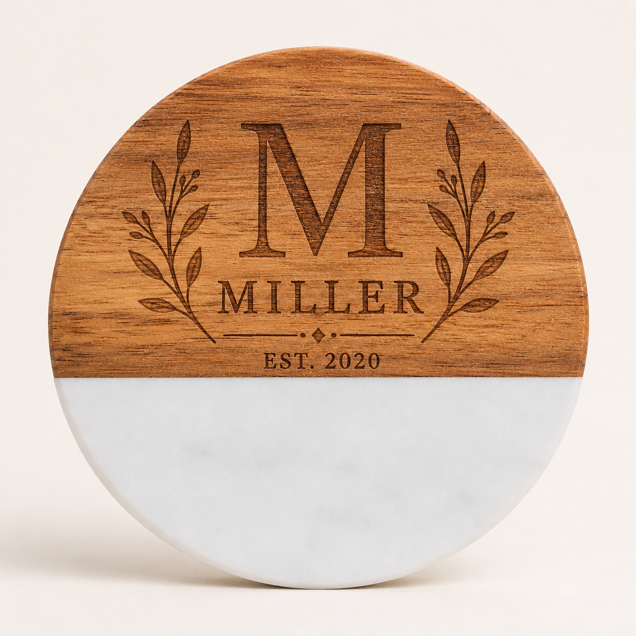 Personalized round marble and acacia wood coaster laser engraved with a Miller family monogram, botanical branches, and established date.