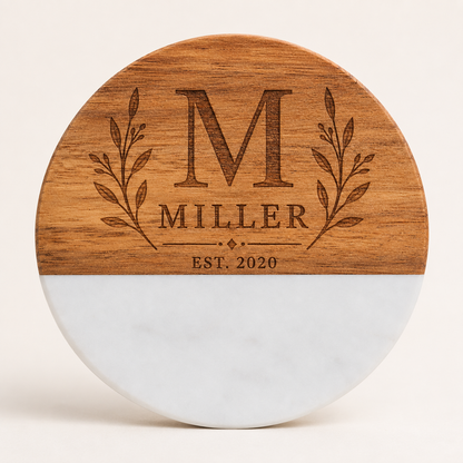 Personalized round marble and acacia wood coaster laser engraved with a Miller family monogram, botanical branches, and established date.