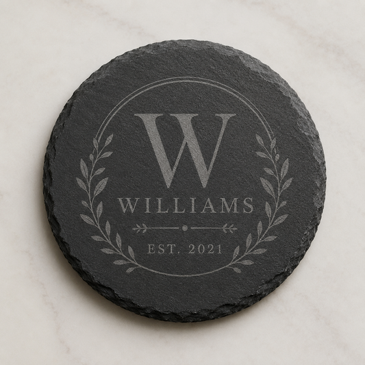 Personalized round slate coaster engraved with a Williams family monogram, laurel design, and established date.