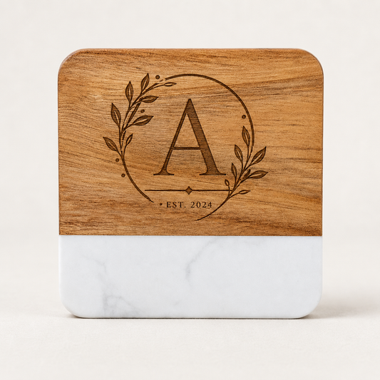 Personalized square marble and acacia wood coaster laser engraved with an elegant botanical monogram and established date.