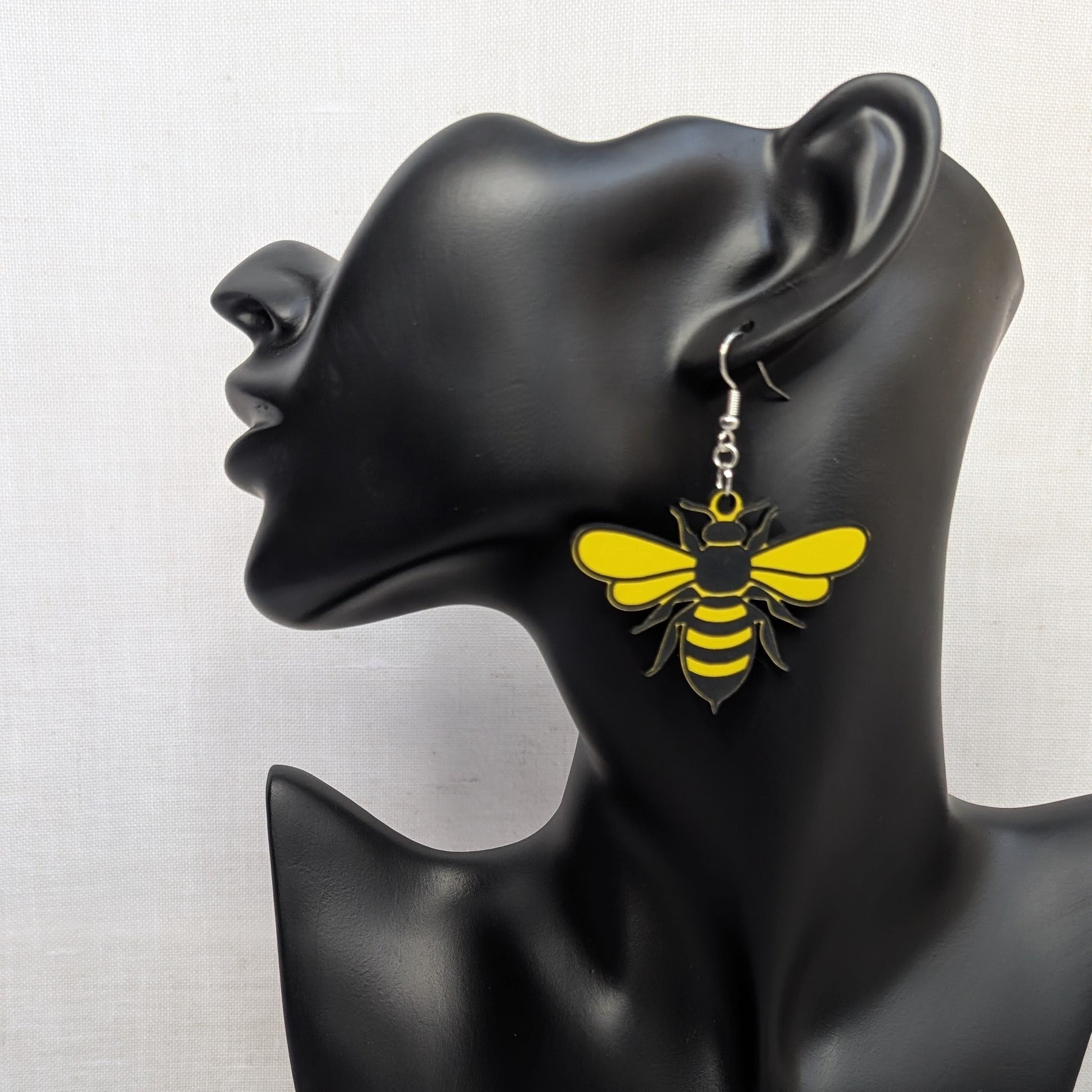 Yellow and black Sweet Buzz-Worthy Bee dangle earring displayed on a black jewelry stand.
