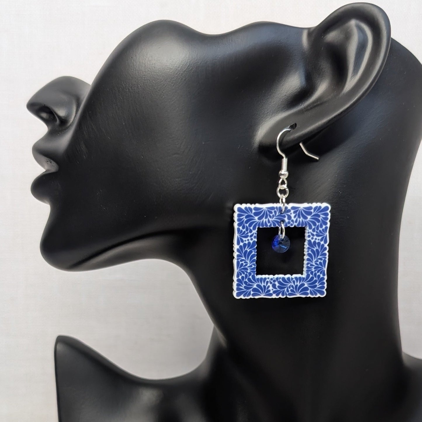 Blue Talavera picture frame earring with a square floral pattern displayed on a black jewelry stand.