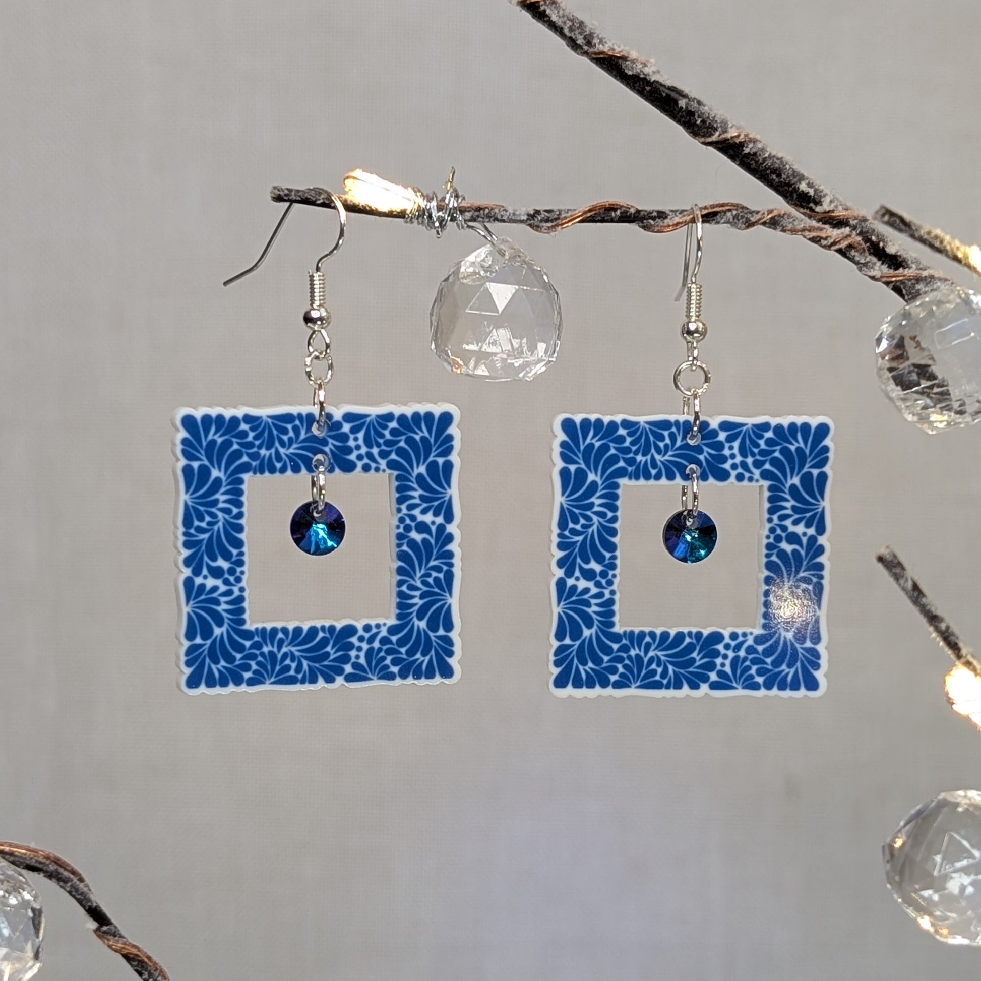 Blue Talavera square earrings with white floral patterns and blue iridescent crystal dangle charms.