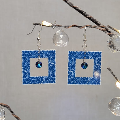 Blue Talavera square earrings with white floral patterns and blue iridescent crystal dangle charms.