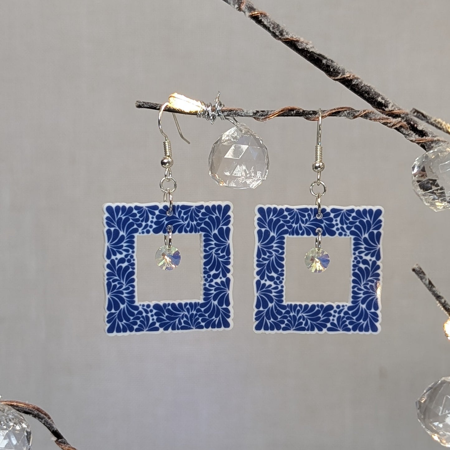 Cobalt blue Talavera square earrings with white floral patterns and iridescent crystal dangle charms.