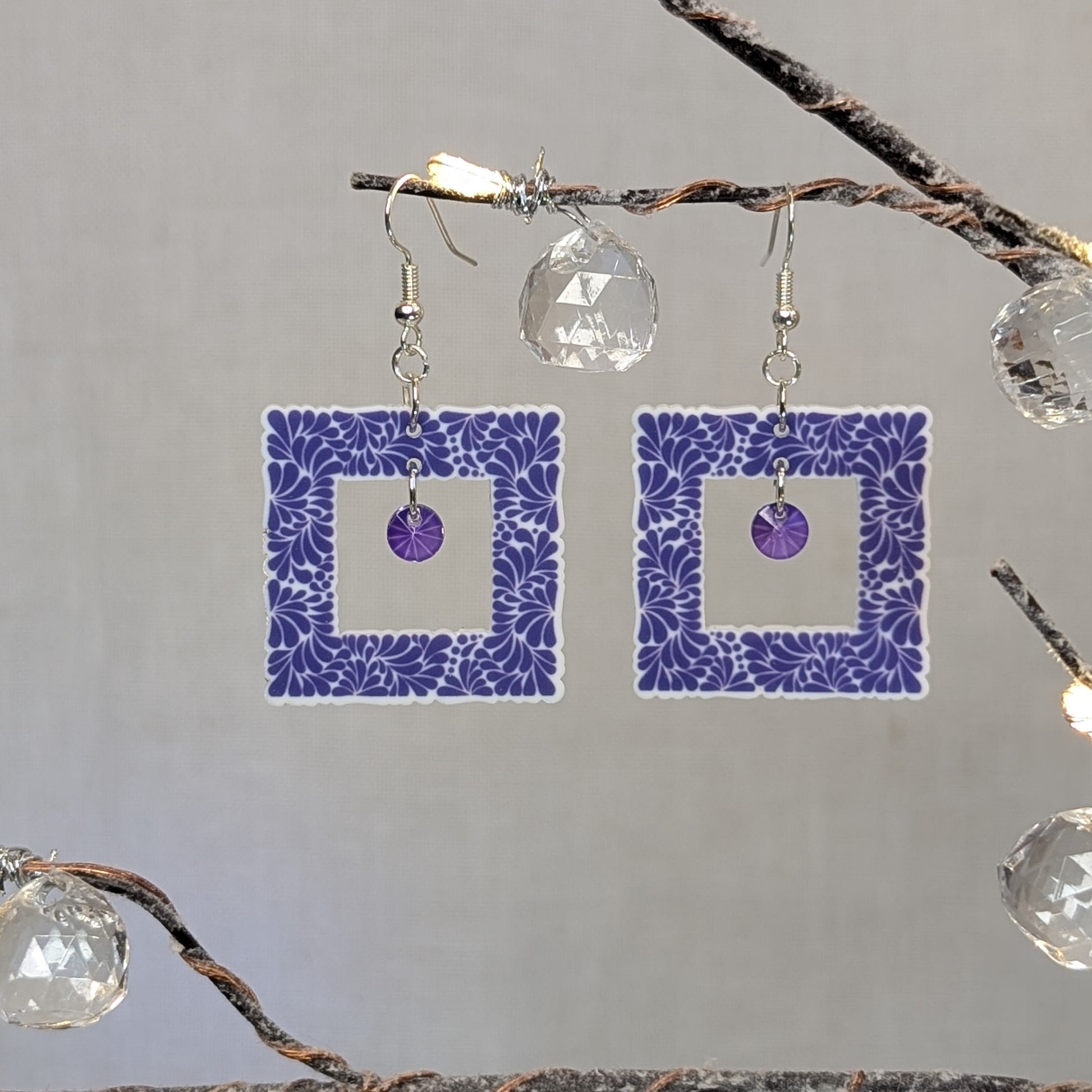 Purple Talavera square earrings with white floral patterns and matching purple crystal dangle charms.