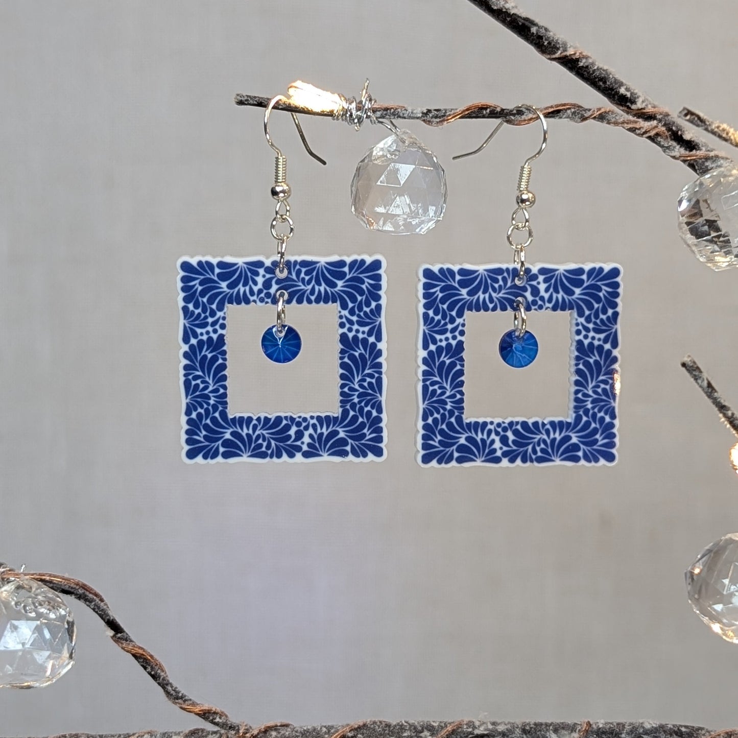 Blue Talavera-style picture frame earrings with white floral patterns and matching blue center charms.