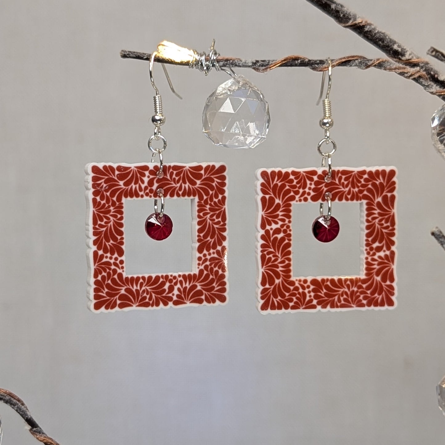 Red Talavera-style picture frame earrings with white floral patterns and matching red center charms.