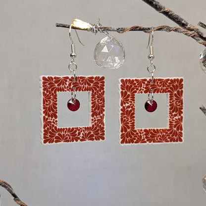 Red Talavera-style picture frame earrings with white floral patterns and matching red center charms.